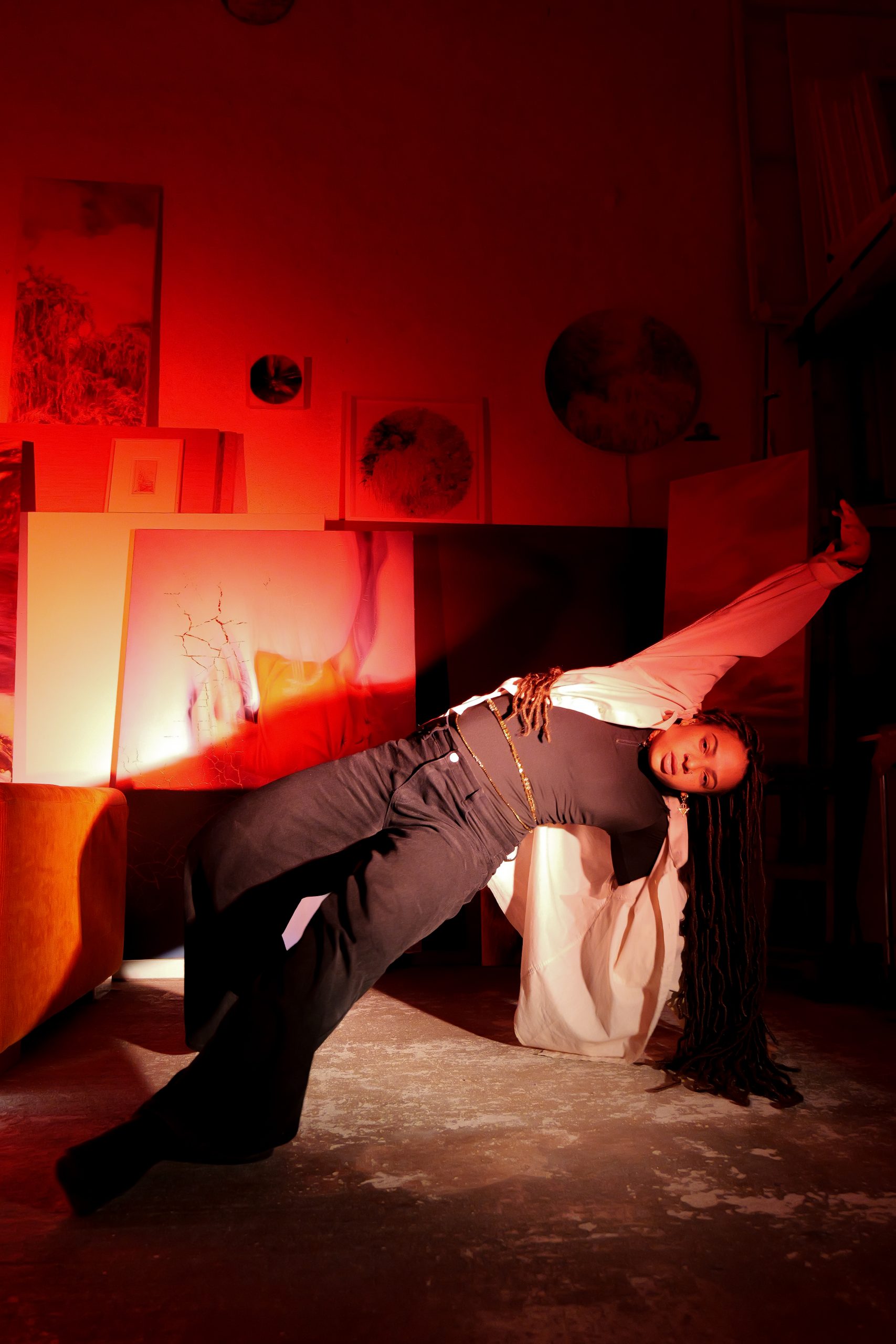Danseuse en mouvement dans un espace artistique baigné de lumière rouge, créant une composition graphique et expressive.